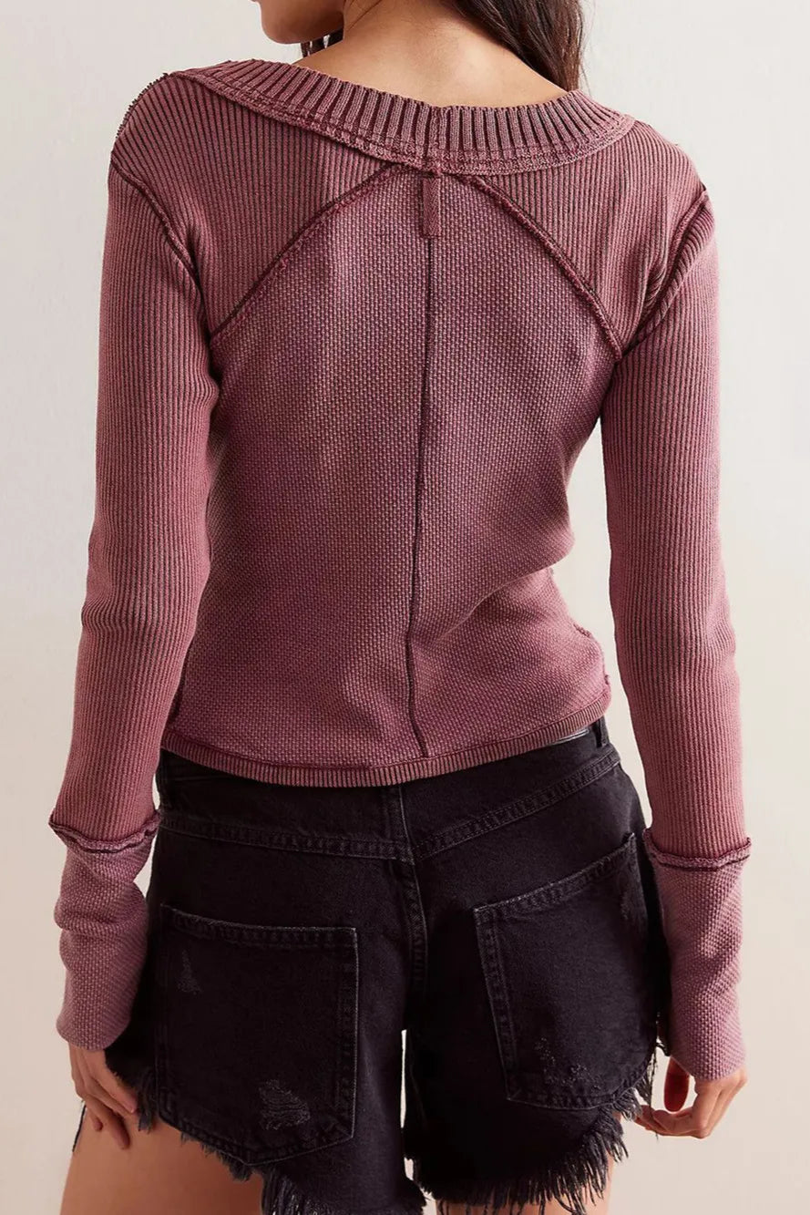 Person wearing a ribbed long-sleeve top with a boat neckline against a plain background