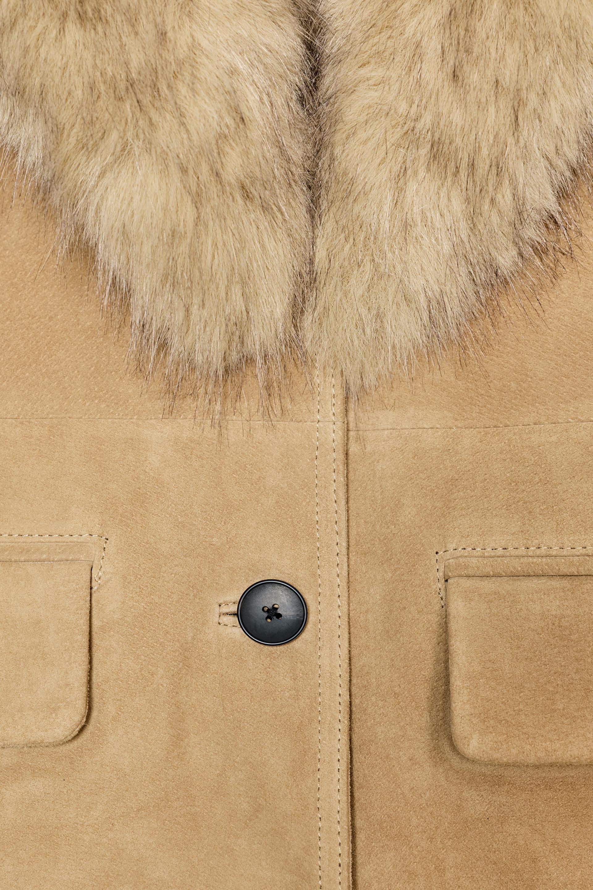 Close-up of a tan coat with fur collar and black button