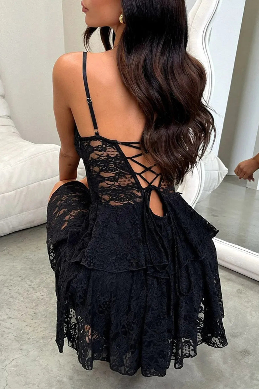 Woman wearing a black lace dress sitting on a white couch.
