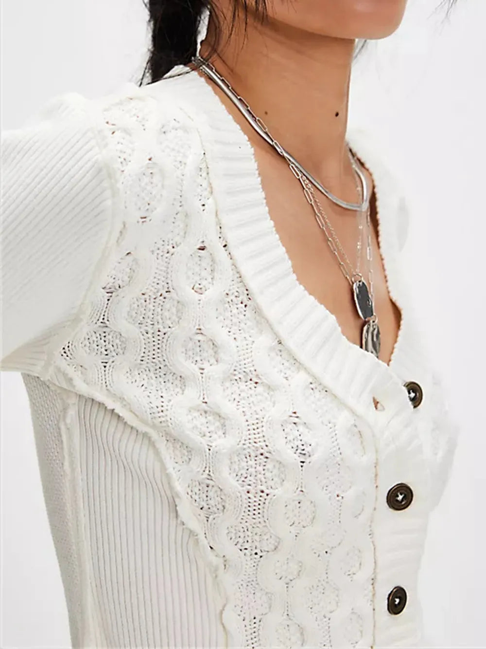 Close-up of a white lace cardigan with buttons on a plain background