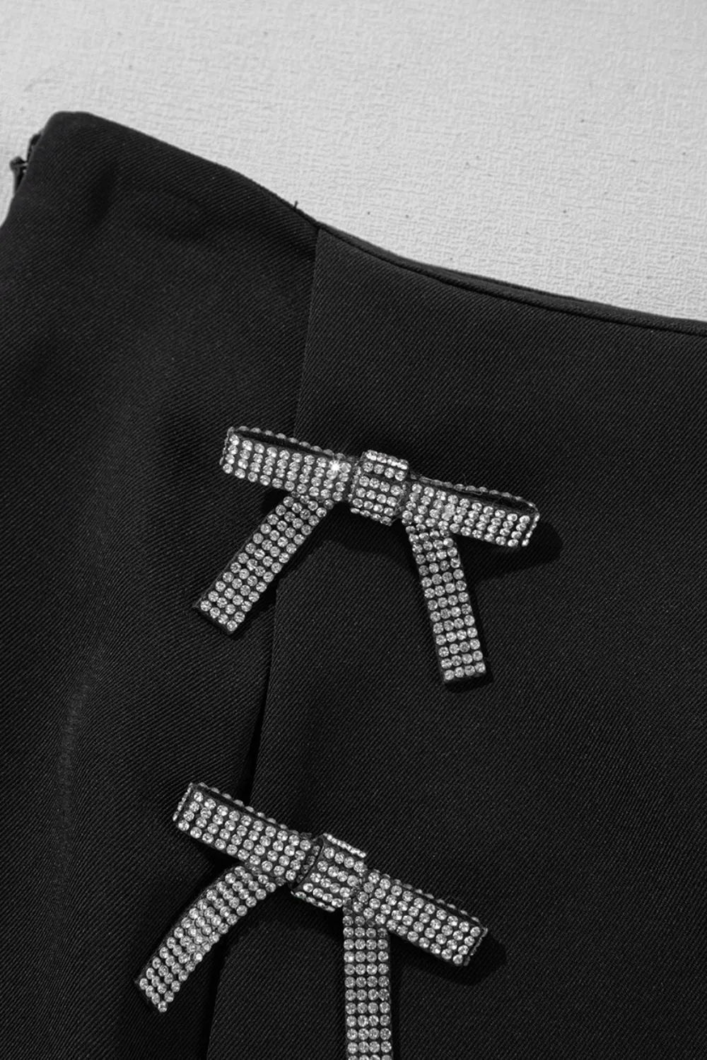 Black fabric with silver bow-shaped embellishments on a gray background