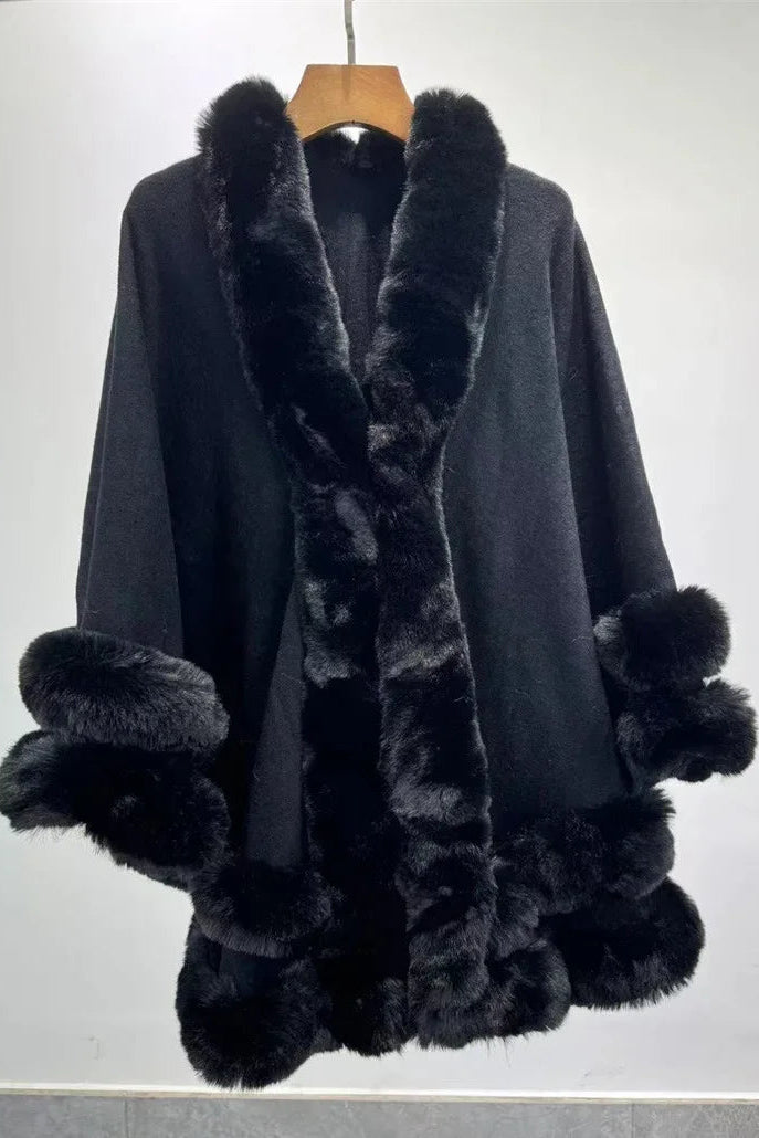 Black cape with fur trim on a wooden hanger against a white background