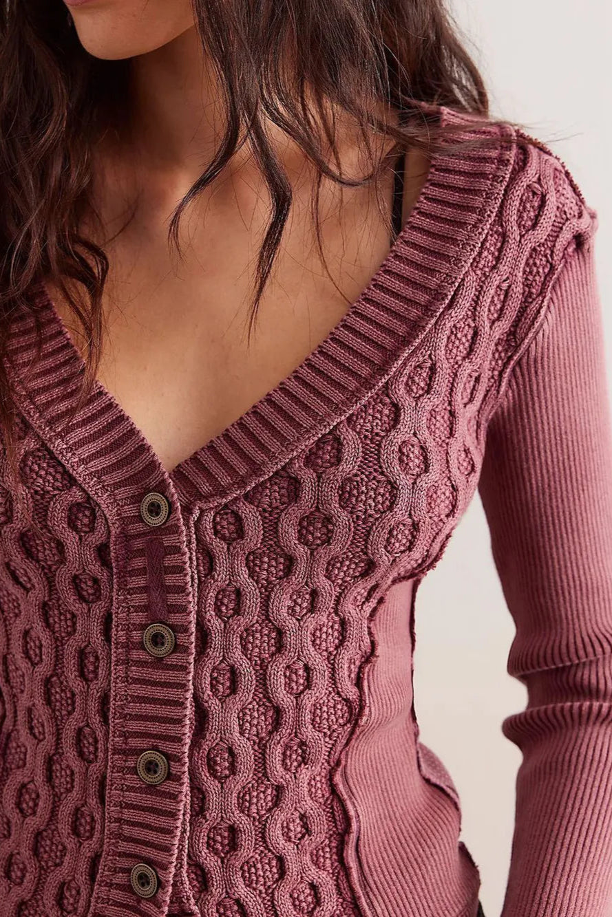 Close-up of a person wearing a textured pink cardigan against a neutral background